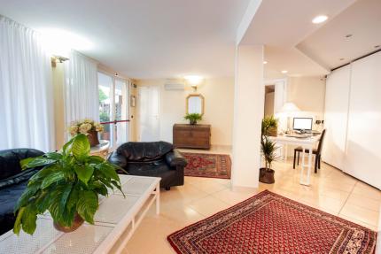 Modern living room with plants, rugs, and a desk.