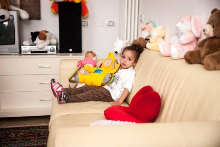 Child sitting on the couch with colorful stuffed animals.