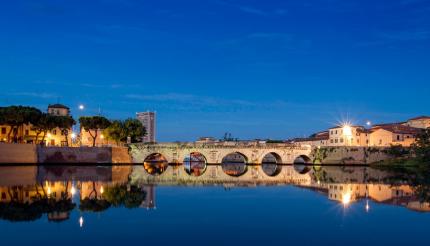 Historic bridge reflected in water at sunset.