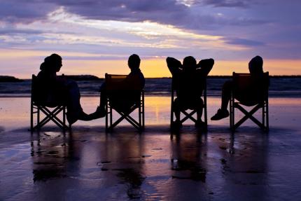 Four people sitting at sunset on the beach.