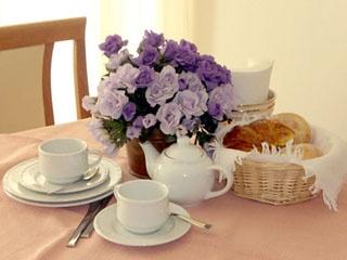 Table set with flowers, tea, and bread.