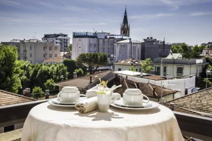 Set table with view of rooftops and bell tower.