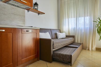 Modern kitchen with sofa bed and sheer curtains.