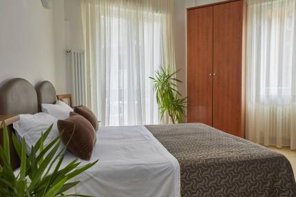 Bright bedroom with plants and wooden wardrobe.