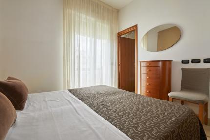 Bedroom with bed, dresser, and curtain.