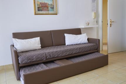 Brown sofa bed with white pillows in bright living room.