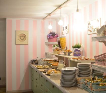 Buffet dolci in sala da tè con decorazioni rosa.