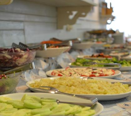 Buffet con verdure fresche e insalate assortite su piatti bianchi.