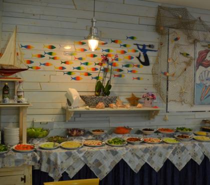 Buffet di insalate in ambiente marittimo con decorazioni colorate.