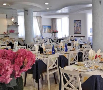 Sala da pranzo elegante con tavoli apparecchiati e decorazioni floreali.