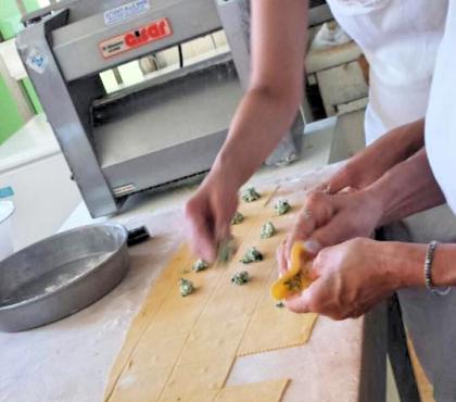 Preparazione di tortellini con ripieno su un piano di lavoro.