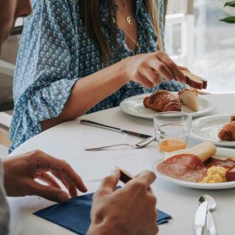 Colazione con croissant, salumi e succo su tavola apparecchiata.