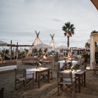 Ristorante sulla spiaggia con luci soffuse e arredi eleganti.