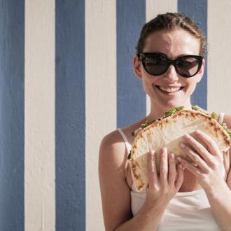 Donna sorridente con occhiali da sole e piadina.