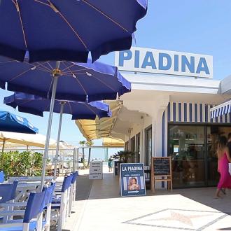 Chiosco di piadine sulla spiaggia con tavoli e ombrelloni blu.