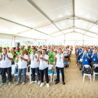 Persone applaudono sotto un tendone sulla spiaggia.