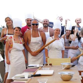 Gruppo di persone con cappelli da chef e grembiuli, sorridenti all'aperto.