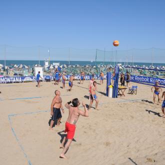 Partita di beach volley su una spiaggia affollata e soleggiata.