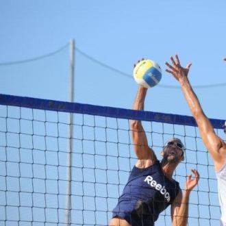 Giocatori di beach volley in azione sotto il sole.