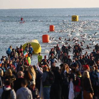 Nuotatori emergono dall'acqua durante una competizione affollata.