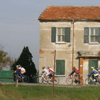 Ciclisti pedalano davanti a una casa rurale in campagna.