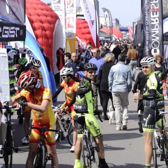 Evento ciclistico con stand e ciclisti in tenuta sportiva.