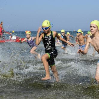 Giovani atleti corrono nell'acqua durante una gara di triathlon.