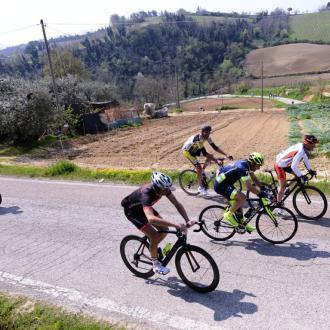 Ciclisti su strada di campagna, giornata soleggiata.