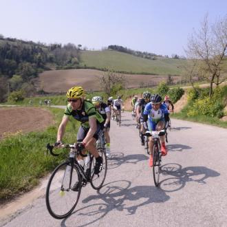 Ciclisti pedalano su una strada di campagna in una giornata soleggiata.