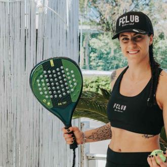 Donna sorridente con racchetta da padel e cappello FCLUB.