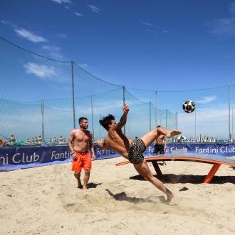 Giocatori su spiaggia praticano teqball, una fusione tra calcio e ping pong.