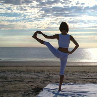 Due persone fanno yoga al tramonto sulla spiaggia.