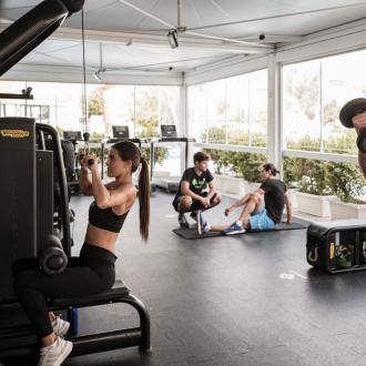 Persone che si allenano in palestra con attrezzi e pesi.