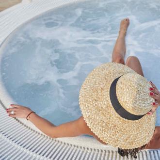 Persona rilassata in jacuzzi con cappello di paglia.