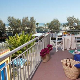 Terrazza con vista mare, lettini e tavolo apparecchiato.