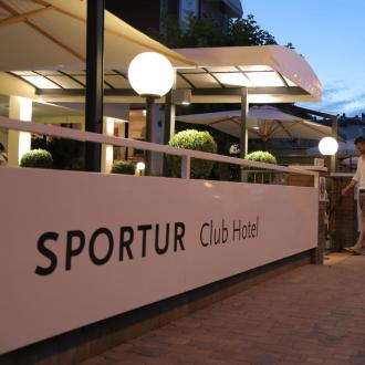 Ingresso serale dello Sportur Club Hotel con coppia in cammino.