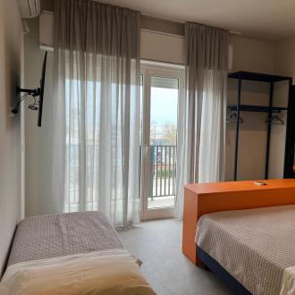 Helles Zimmer mit Bett, modernem Bad und Balkon.