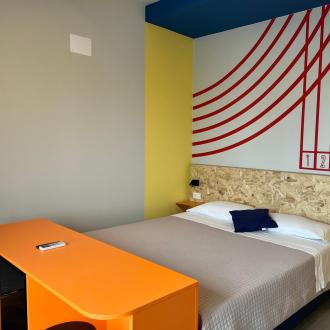 Moderne, bunte Zimmer mit Doppelbett und geometrischen Dekorationen.