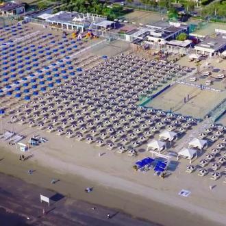 Spiaggia attrezzata con ombrelloni, campi sportivi e strutture ricreative.