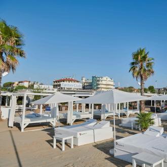 Spiaggia elegante con lettini bianchi e palme al Fantini Club.