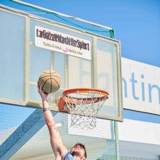 Giocatore di basket schiaccia a canestro all'aperto.