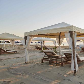 Gazebo sulla spiaggia con lettini al tramonto.