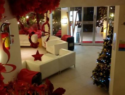 Sala d'attesa decorata per Natale con albero e ornamenti rossi.