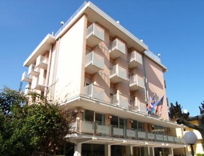 Edificio moderno con balconi e bandiere, cielo blu sullo sfondo.