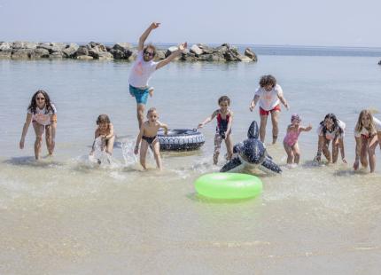 Gruppe von Menschen, die im Meer mit aufblasbaren Spielzeugen spielen.