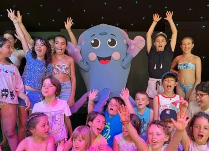 Glückliche Kinder posieren mit einem Maskottchen auf der Bühne.