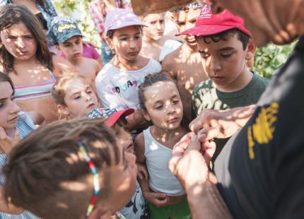 Neugierige Kinder beobachten einen Erwachsenen, der etwas in der Natur zeigt.