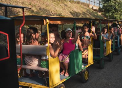 Lächelnde Kinder auf einem Freiluftzug, genießen die Sonne.