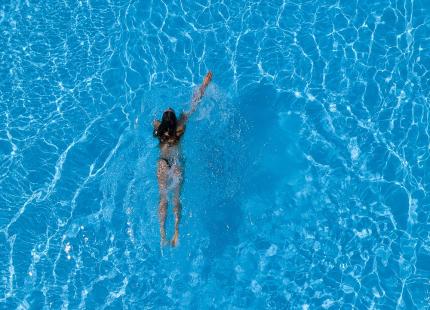 Person schwimmt im Pool, von oben gesehen.