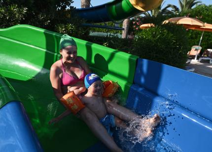 Familienspaß auf einer grünen und blauen Wasserrutsche.